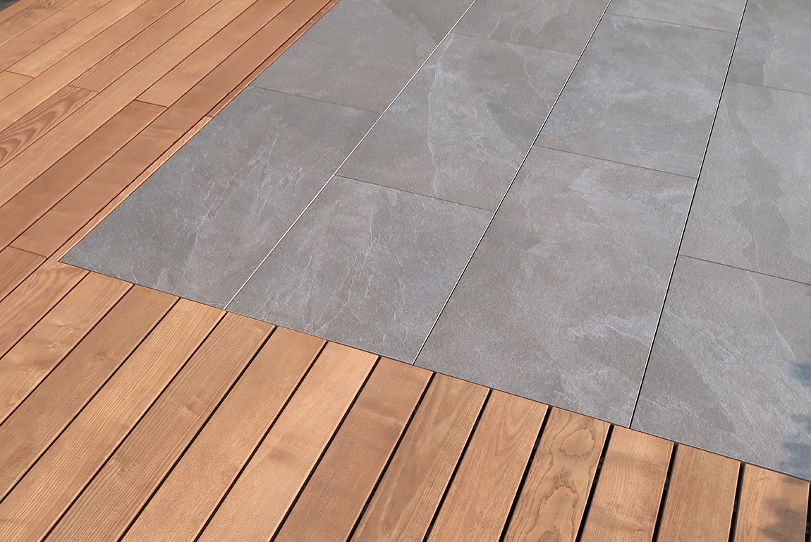 Keramische Platten Ardesia von Karle & Rubner in grau bilden einen schönen Kontrast mit einem Terrassenholzboden.